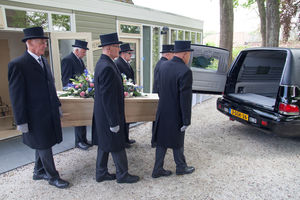 De dragers brengen de kist naar de rouwauto