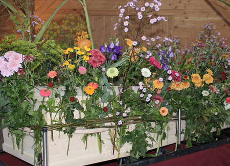 rouwbloemen op een andere manier: rondom de kist, gestoken tussen wilgentenen