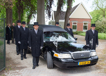dragers begeleiden de rouwauto - een traditionele uitvaart vanuit aula Memory in Warffum