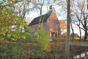 De romaanse Sint-Nicolaaskerk met een gracht er om heen